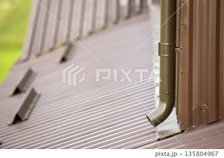 Close-up of brown new gutter metal system pipe on wall. Drain protection, professional work concept. Close-up of brown new gutter metal system pipe on wall. Drain protection, professional work concept. 135804967
