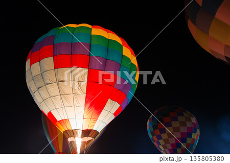 colorful hot air balloons glowing against dark night sky colorful hot air balloons glowing against dark night sky 135805380