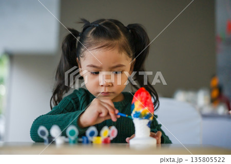 child girl painting plaster statue on table 135805522