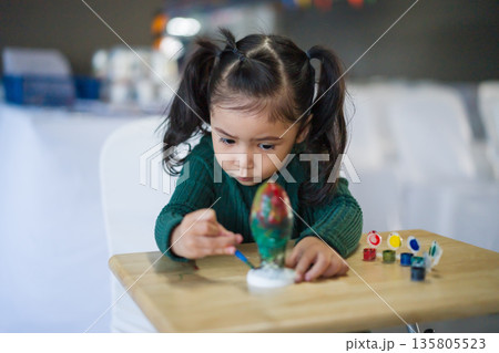 child girl painting plaster statue on table child girl painting plaster statue on table 135805523
