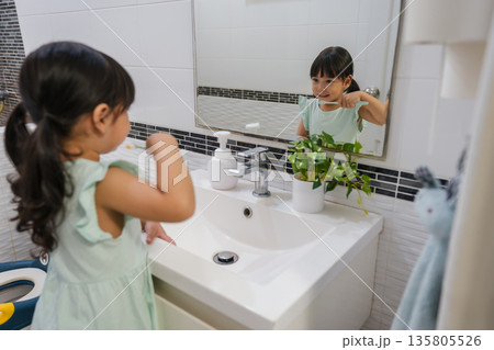 girl child brushing teeth at reflection in mirror in bathroom girl child brushing teeth at reflection in mirror in bathroom 135805526