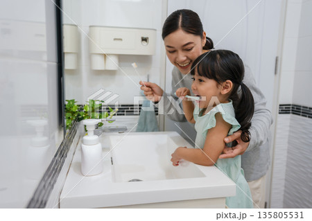 mother teaching girl child to brushing teeth in bathroom mother teaching girl child to brushing teeth in bathroom 135805531