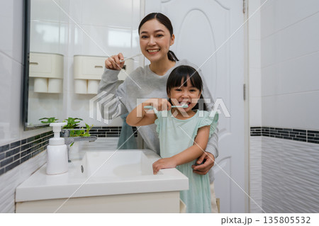 mother teaching girl child to brushing teeth in bathroom 135805532
