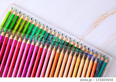 Set of colored pencils with various colors is neatly arranged in plastic case on flat surface. 135805648