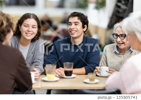 older generation of the family communicates with their grandchildren in a cafe 135805741
