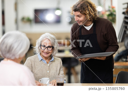 Male waiter brings order to elderly women 135805760