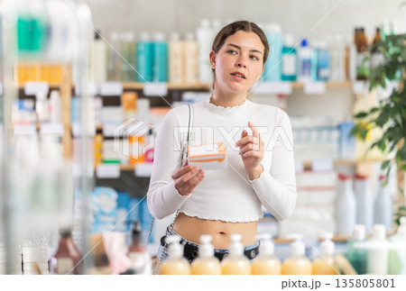 woman in summer clothes chooses a package of pallets in a pharmacy woman in summer clothes chooses a package of pallets in a pharmacy 135805801