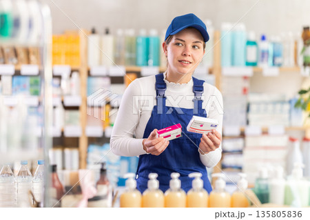 In sales area of pharmacy, builder woman examines packaging of paracetamol pill In sales area of pharmacy, builder woman examines packaging of paracetamol pill 135805836