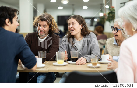 Positive family talking cheerfully and drinking wine at table in cafe Positive family talking cheerfully and drinking wine at table in cafe 135806031