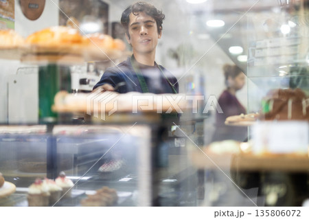 Waiter guy laying out desserts on the counter 135806072