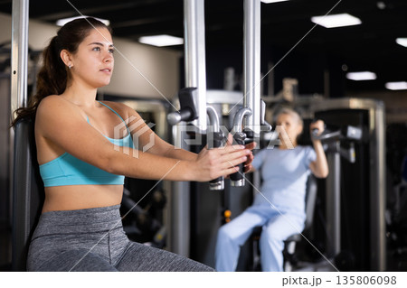 Fit young woman working out at chest fly machine Fit young woman working out at chest fly machine 135806098