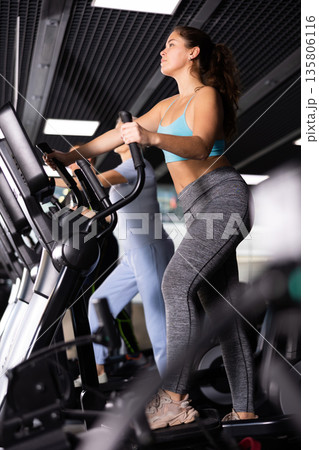 Young girl working out on elliptical machine in gym 135806116