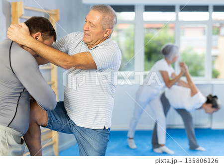Old man practicing self-defense techniques in pairs 135806126