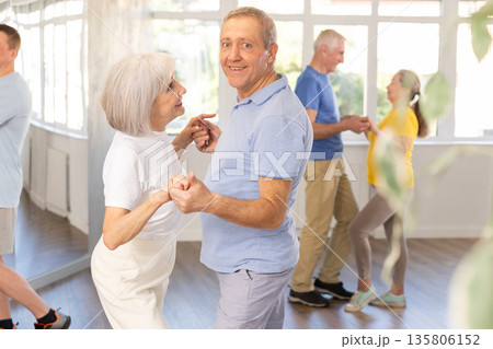 Elderly man enjoying merengue with female partner in latin dance class 135806152