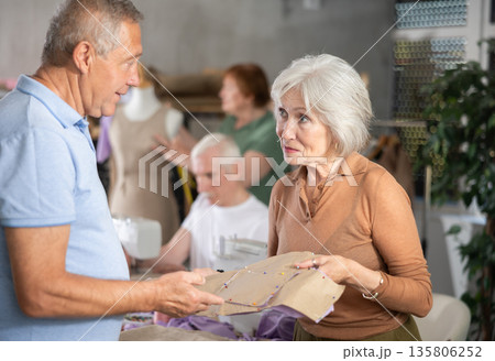 Some people discuss pattern, while others sew using sewing machine, work with mannequin Some people discuss pattern, while others sew using sewing machine, work with mannequin 135806252