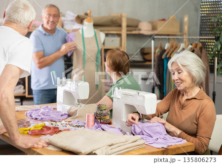 Elderly male teacher showing how to sew on mannequin Elderly male teacher showing how to sew on mannequin 135806273