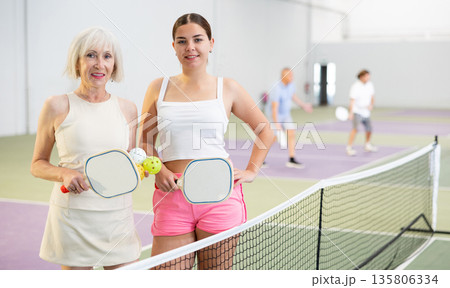 Two smiling female pickleball players standing on indoor court 135806334