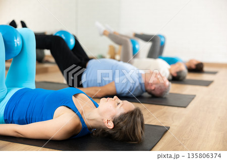 Woman exercising with bender ball during group training at gym. Woman exercising with bender ball during group training at gym. 135806374