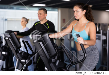 Fitness woman in sportswear doing cardio training on ellipsoid in gym Fitness woman in sportswear doing cardio training on ellipsoid in gym 135806419