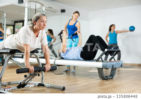 Elderly woman doing stretching exercises on pilates chair 135806448
