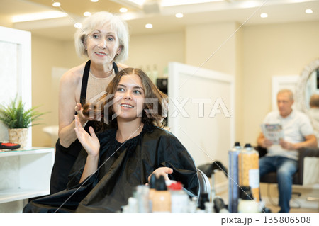 Elderly woman hairdresser master does discusses with client length of hair, shape of haircut Elderly woman hairdresser master does discusses with client length of hair, shape of haircut 135806508