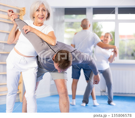Old woman twisting her opponent's arm during self-defense classes Old woman twisting her opponent's arm during self-defense classes 135806578