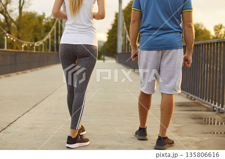 Fitness couple walking on park bridge at sunrise, sporty legs and sneakers 135806616