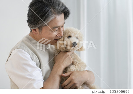 愛犬（ビションプーの10ヶ月の女の子）を抱っこする50代の男性　犬との暮らしイメージ 135806693