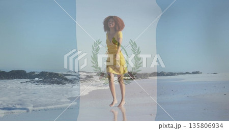 Walking woman wearing yellow short-sleeved dress barefoot on wet beach, near gentle waves and rocks Walking woman wearing yellow short-sleeved dress barefoot on wet beach, near gentle waves and rocks 135806934