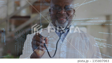Holding stethoscope doctor wearing lab coat pointing toward viewer in clinic, with code overlay 135807063