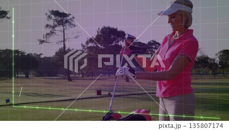 Woman pulling headcover over golf club on golf course, wearing polo, with golf bag, copy space 135807174