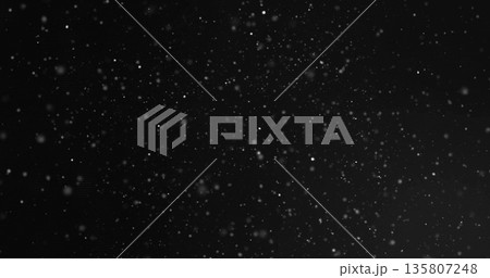 Drifting white snowflakes creating textured depth in nighttime outdoors, with glowing particles 135807248