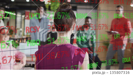 Presenting woman in purple blouse demonstrating codes on glass board in open office with laptops Presenting woman in purple blouse demonstrating codes on glass board in open office with laptops 135807316