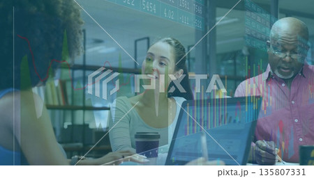 Collaborating professionals analyzing financial charts around table in meeting room, with laptop 135807331