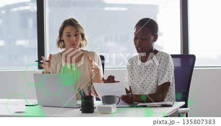 Discussing professionals wearing business attire reviewing documents at office desk with laptop 135807383