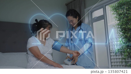 Nurse wearing blue scrubs wrapping blood pressure cuff around patient arm in bedroom 135807421