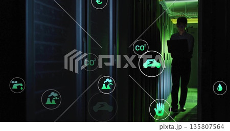 Technician checking server energy in data center corridor, with glowing icons on laptop, copy space 135807564