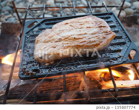 焚き火で肉を焼くアウトドアキャンプの調理風景 焚き火で肉を焼くアウトドアキャンプの調理風景 135807774