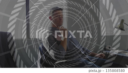 Leaning man wearing button-down shirt and jeans at office window, with desk lamp headphones 135808580