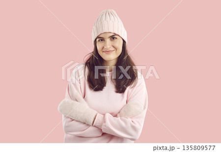 Portrait of happy beautiful young woman in warm pink winter hat, sweatshirt and mittens Portrait of happy beautiful young woman in warm pink winter hat, sweatshirt and mittens 135809577