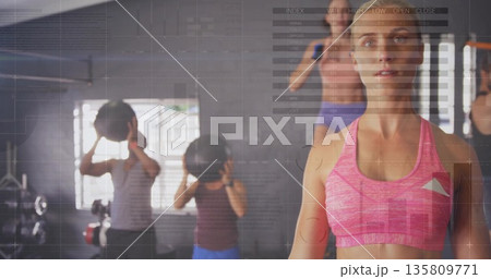 Trainer in sportswear guiding group using medicine balls in gym, with data overlays, copy space 135809771