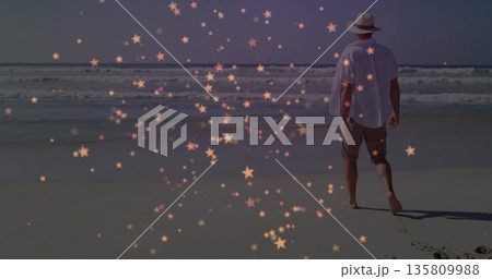 Walking hat-wearing man in shorts pacing barefoot along beach, with star-shaped overlay, copy space 135809988