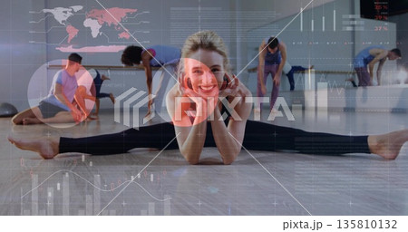 Smiling instructor in leggings performing side split in studio with wood floor, mirror AR overlays Smiling instructor in leggings performing side split in studio with wood floor, mirror AR overlays 135810132