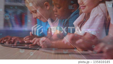 Leaning schoolchildren tapping tablets in classroom, with wooden desk and books on shelves Leaning schoolchildren tapping tablets in classroom, with wooden desk and books on shelves 135810185