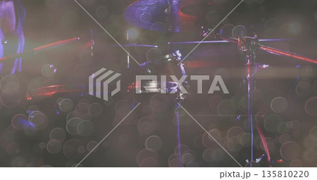 Glinting drum kit catching red spotlights on music venue stage, with haze and microphone stands Glinting drum kit catching red spotlights on music venue stage, with haze and microphone stands 135810220