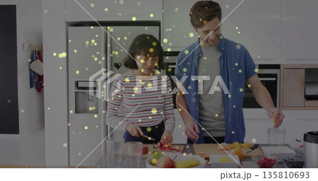 Couple chopping assorted fruits on home kitchen island, with cutting board blender and glass cups 135810693