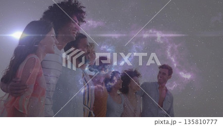 Standing group of eight friends linking arms and smiling in open field under cosmic nebula 135810777