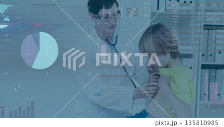 Listening doctor pressing stethoscope on school-age boy's chest in clinic, with digital charts 135810985