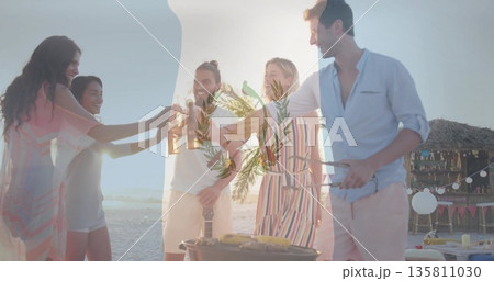 Toasting beers five friends standing at grill on sandy beach at sunset, with tiki bar lights Toasting beers five friends standing at grill on sandy beach at sunset, with tiki bar lights 135811030