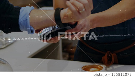 Tapping smartwatch on handheld POS terminal at coffee shop counter, showing latte foam art 135811075